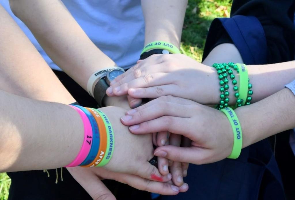 showing support hands with beads and bracelets stacked in a show of support at an out of darkness t20 29LXeZ