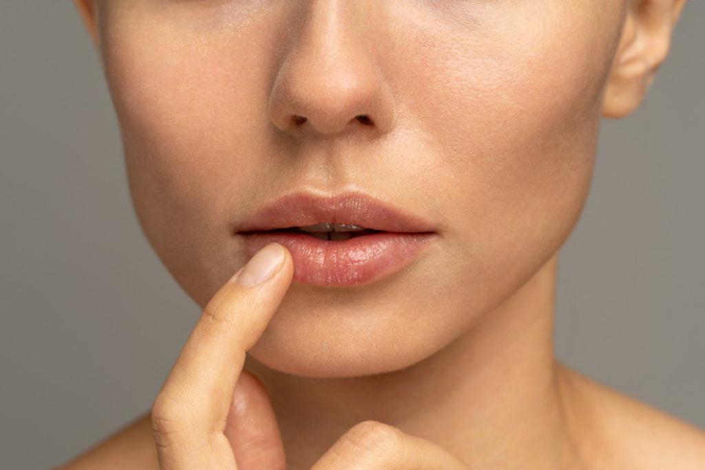 close up of woman applying moisturizing nourishing balm to her lips with her finger to prevent t20 6Y3K2p