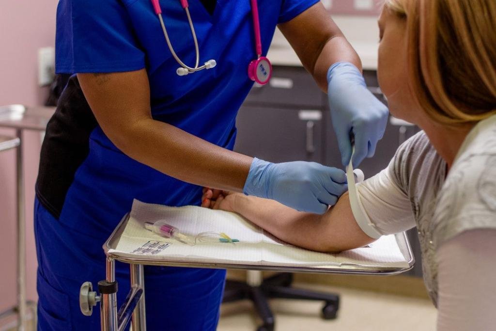 medical assistant putting a tourniquet around a patients arm before she draws blood t20 yRdERR