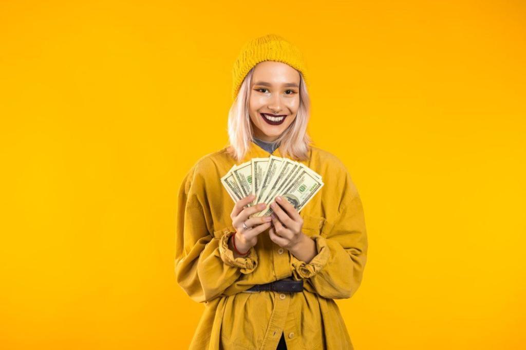 satisfied happy excited unusual teen girl showing money u s currency dollars banknotes on yellow wall t20 O077y8