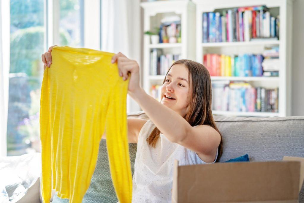 happy young teenager girl smiling while unpacking parcel with colorful clothes gift