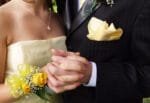 Close-up of a girl wearing a yellow strapless dress, and a boy in a black suit, a yellow tie, and a yellow handkerchief.
