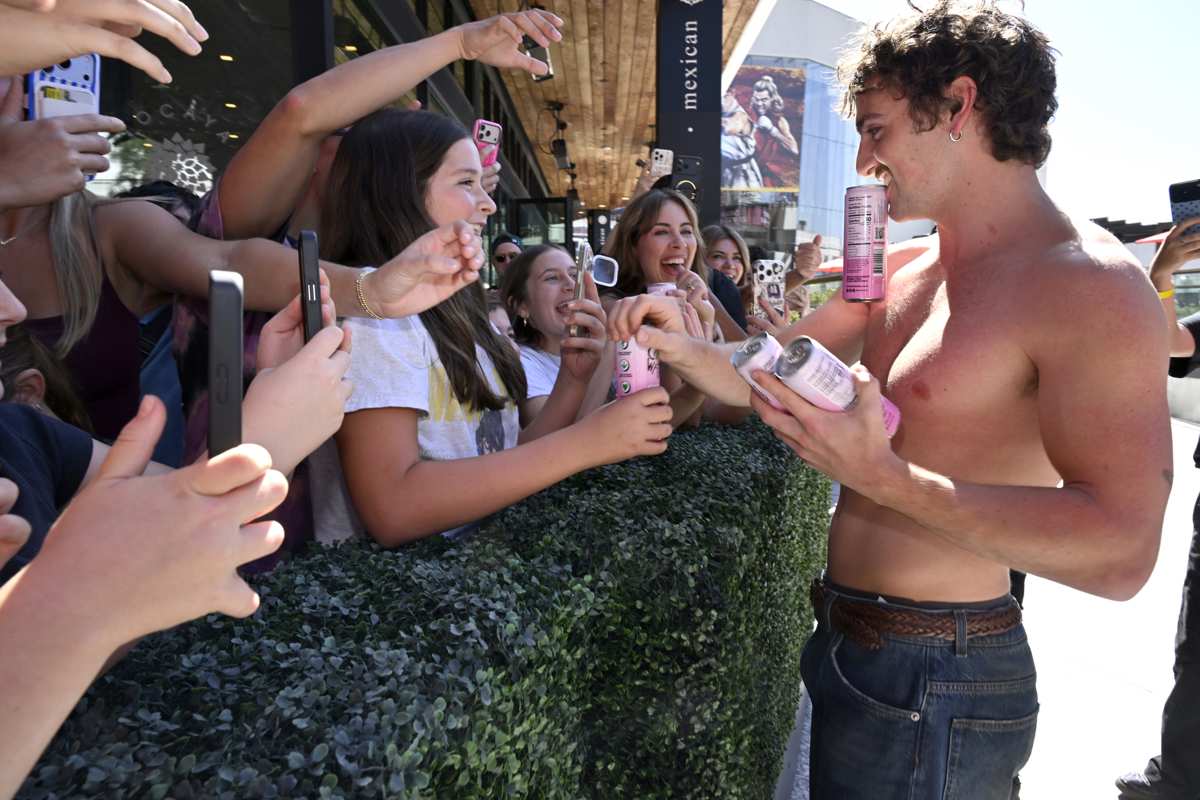 Fans reach out as Benson Boone hands out Caliwater cans at the launch.