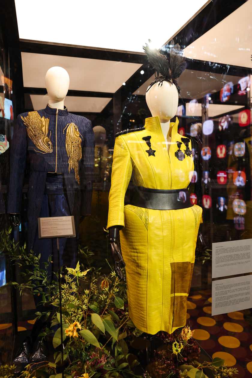 Two embellished costumes displayed in a glass case at the Panem exhibition